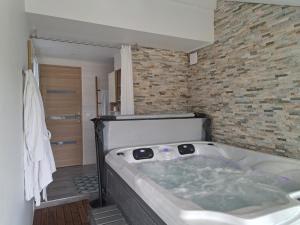 eine Badewanne in einem Badezimmer mit einer Ziegelwand in der Unterkunft Adorelys séjour bien être - spa et massage in Saint-Cassien + 13 Fotos