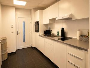 a kitchen with white cabinets and a sink and a door at Schängel Chic 03 in Koblenz