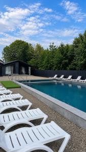 a row of white lounge chairs next to a swimming pool at Forest Solotvyno in Solotvyno