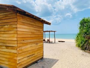 a wooden building on the beach with a bench at Lima Blue Private Beach Apartment in Trincomalee