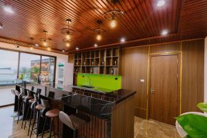 a kitchen with a bar with stools and a green island at Biệt Thự FLC Sầm Sơn 7PN VIP BT43-02 in Sầm Sơn +40 photos