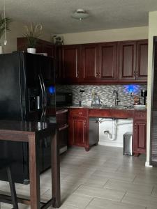 a kitchen with wooden cabinets and a black refrigerator at Clearwater Beach Getaway Clearwater in Clearwater