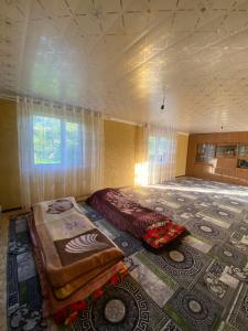 a room with two beds and a large rug at Bloom Guest House in Tërt-Kul'