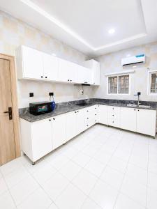 a kitchen with white cabinets and a white tile floor at Nathivian Apartment in Mobushipe