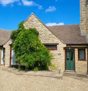 a brick house with a green door and a bush at A quiet gem just outside Oundle in Oundle