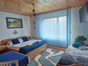 a bedroom with two beds and a large window at Penzión Daria in Batizovce