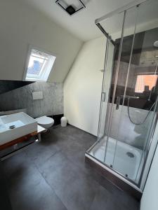 a bathroom with a shower and a toilet and a sink at Hotel Meereswoge in Cuxhaven +34 photos