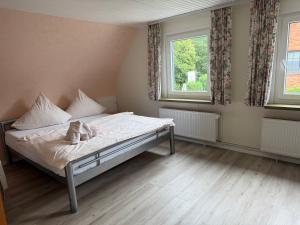 a small bedroom with a bed and two windows at Hotel Meereswoge in Cuxhaven