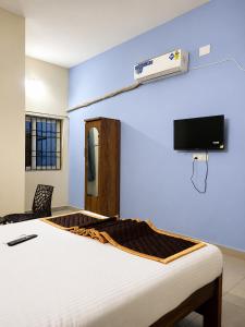 a bedroom with a bed and a tv on the wall at Hotel Far-Inn in Irungattukottai
