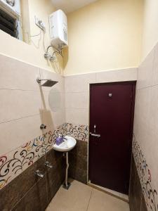 a bathroom with a sink and a black door at Hotel Far-Inn in Irungattukottai