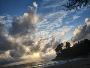 a cloudy sky over a beach with people on it at enDanni Bed in Ban Phak Chit