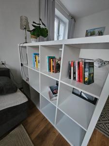 a white book shelf filled with books next to a couch at Blick auf die Kirche in Wschowa