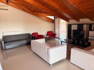 a living room with a couch and red chairs at Sonya Apartments in Mesochórion