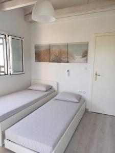 two beds in a room with white walls and windows at Valimitika beach house - Just 150m from the beach in Valimítika