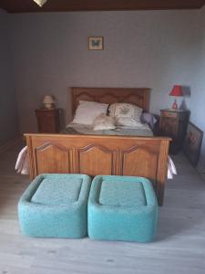 a bedroom with a bed with two blue ottomans at Chez Danielle in Saint-Georges-de-Baroille