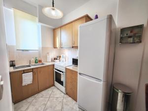 a kitchen with a white refrigerator and wooden cabinets at Akrata Maisonette in Akrata