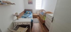 a small bedroom with a bed and a crib at Sabina Apartmani in Tuzla