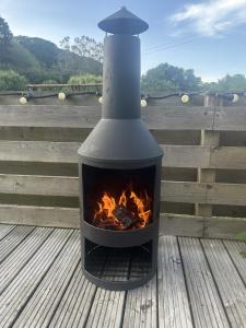 a fireplace sitting on a deck with a fire at Willow Valley Glamping in Bude