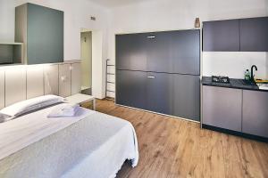 a bedroom with a large white bed and a kitchen at Affittacamere Sanbenedetto in San Benedetto del Tronto