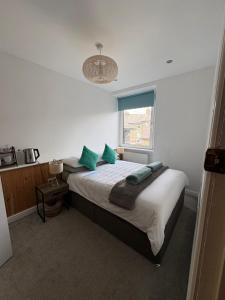 a bedroom with a bed with green pillows and a window at Birch Tree House in Windermere