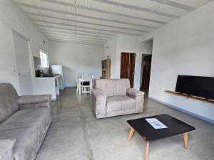 a living room with a couch and chairs and a flat screen tv at CASA Les Deux R da Lagoa in Jijoca de Jericoacoara