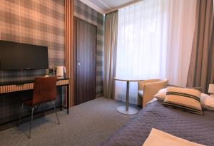 a hotel room with a bed and a desk and a television at Pensjonat Irena in Muszyna