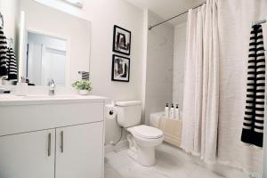 a white bathroom with a toilet and a sink at Central 5 Bedroom AC Rogers Commonwealth EXPO in Edmonton +198 photos