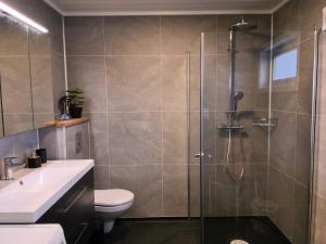 a bathroom with a shower and a toilet and a sink at Modern 1BR City Centre Apt - Sleeps 4 in Otta +5 photos