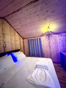 a bedroom with a white bed in a wooden room at Flori's House in Valbonë