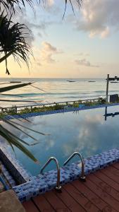 Ein Swimmingpool mit dem Meer im Hintergrund in der Unterkunft Coco Beach Hotel in Jambiani