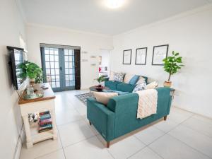 a living room with a blue couch and a tv at Ivory Pearl in Paternoster +4 photos