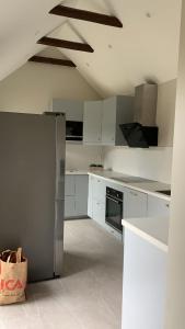 a kitchen with white cabinets and a stainless steel refrigerator at Tivoligatan in Höganäs +8 photos