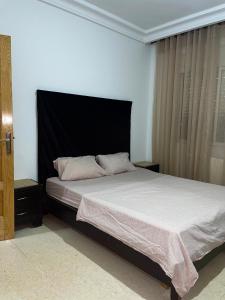 a bed with a black headboard in a bedroom at Sweet Home in Tunis