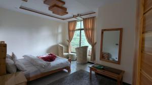 a bedroom with a bed and a mirror and a table at Cool Pine Hotel Nathia Gali in Abbottabad