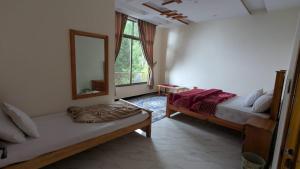 a bedroom with two beds and a mirror and a window at Cool Pine Hotel Nathia Gali in Abbottabad