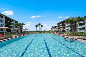 a swimming pool at a resort with two people swimming at Beachfront End Unit 302 2 Bikes beach gear in Sanibel