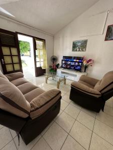 a living room with two couches and a flat screen tv at Appt Cosy Belcourt in Baie-Mahault