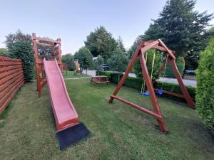 a playground with a slide and a swing set at domek Lawendowy na wiejskiej in Lubiatowo