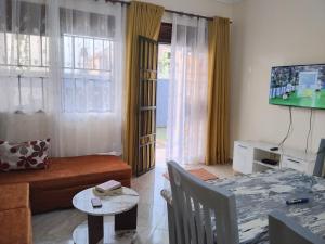 a living room with a couch and a table and a television at Rose Pearl Apartment in Entebbe