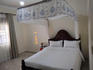 a bedroom with a large white bed with a canopy at Rose Pearl Apartment in Entebbe