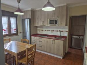 a kitchen with wooden cabinets and a wooden table with a dining room at Casa Güelo in Muros de Nalón +16 photos