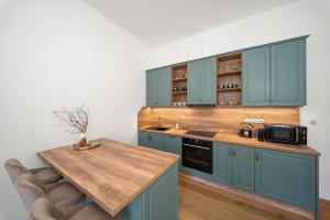 a kitchen with blue cabinets and a wooden table at Zámecký Apartmán Verde in Jince