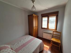 a bedroom with a bed and a chair and a window at Casa Güelo in Muros de Nalón