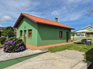 a small green house with a patio and flowers at Casa Güelo in Muros de Nalón