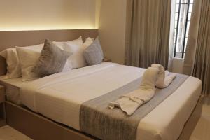 a bedroom with a large bed with white sheets and pillows at Hotel Nevesa Devanahalli in Bangalore