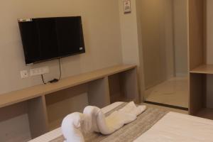 a room with a bed with a television and a towel pile at Hotel Nevesa Devanahalli in Bangalore