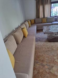a long couch with yellow pillows in a living room at Villa Saif in Marina Smir