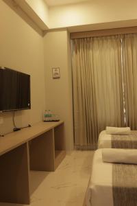 a hotel room with two beds and a desk with a television at Hotel Nevesa Devanahalli in Bangalore +15 photos