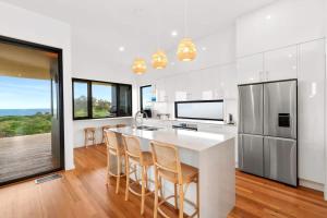 a kitchen with a large white island with bar stools at Dunes at Tomakin in Tomakin
