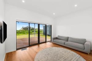 a living room with a couch and a large window at Dunes at Tomakin in Tomakin +8 photos